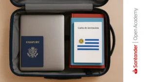 Maleta con laptop, pasaporte, libros y carta de invitación con bandera de Uruguay